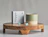 Grey printed product box beside a candle and blue tablets on a wooden stand