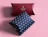Top-down view of two pillow boxes, one dark red and one blue with a white star pattern, on a pink background