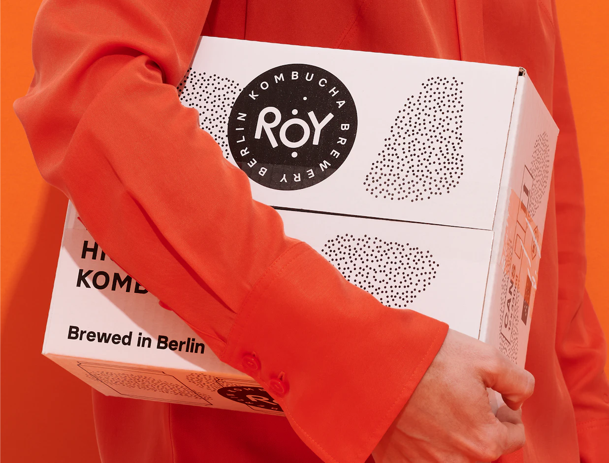Person carrying white shipping boxes with a black circular logo print