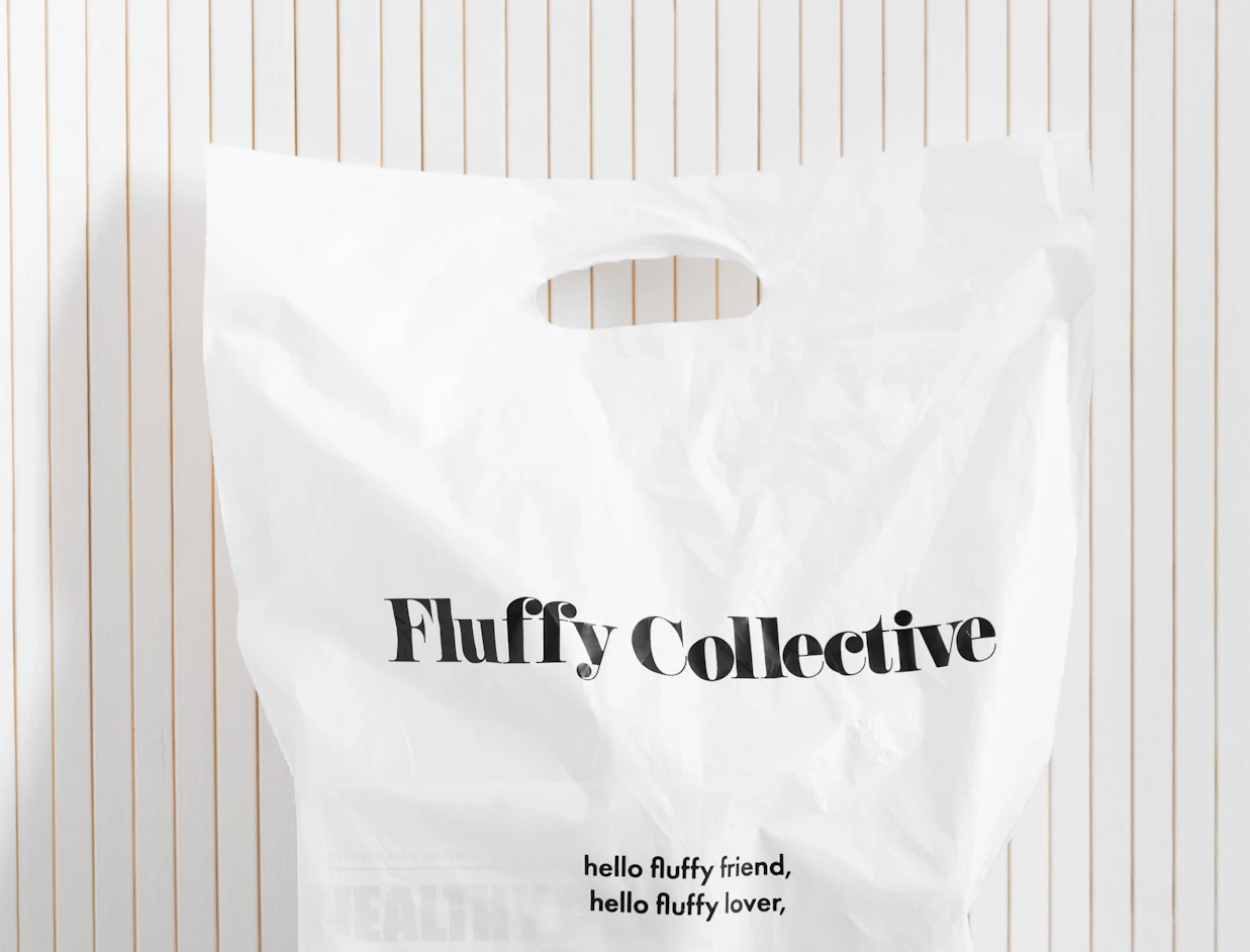 White bio poly mailer with a black logo print and die-cut handle against a panelled wall