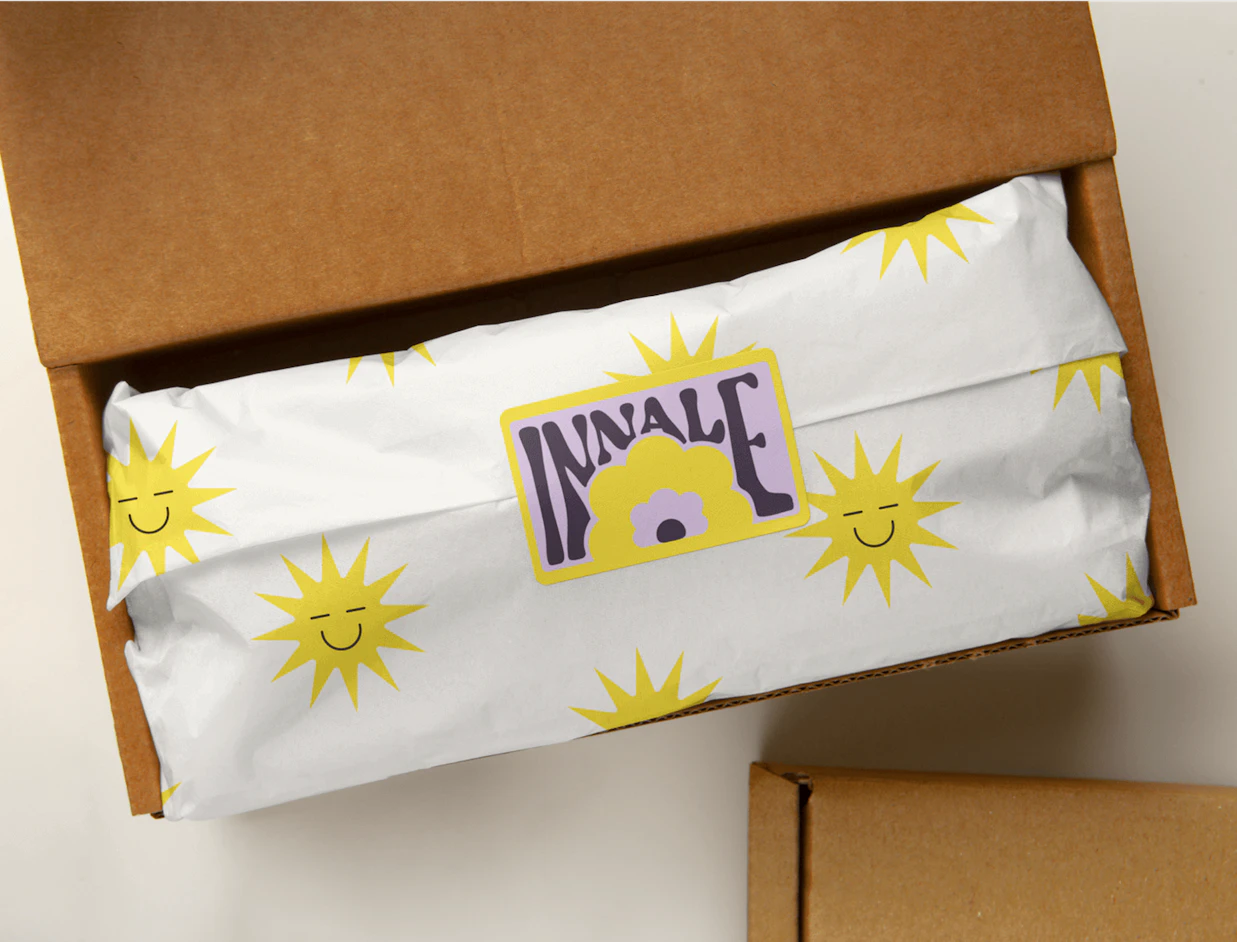 White poly mailer with a sun pattern inside a kraft box, sealed with a rectangular custom label