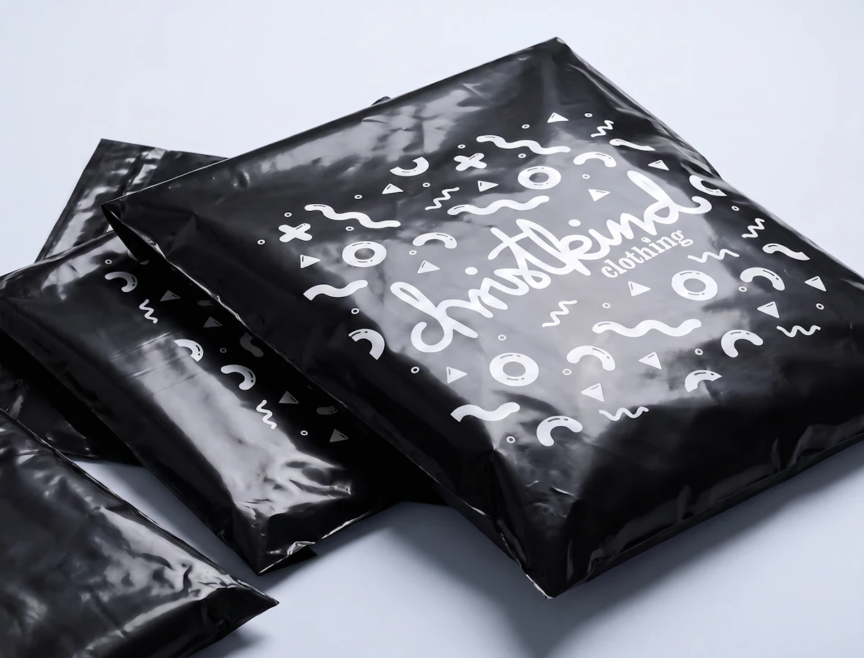 Stack of glossy black poly mailers printed with white playful geometric patterns and the logo 'christkind clothing'