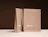 Two expandable kraft mailers with a white print standing upright on a dark backdrop