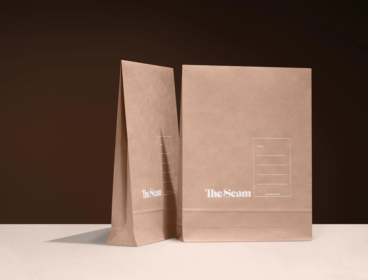 Two expandable kraft mailers with a white print standing upright on a dark backdrop