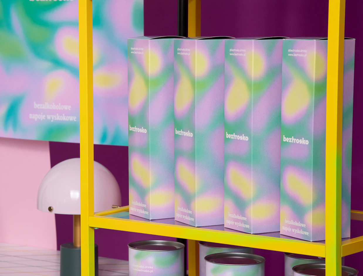 Tall bottle boxes with a colorful pastel gradient design branded 'beztrosko' arranged on a bright yellow shelf