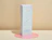 Three light blue cube boxes stacked vertically on a pink acrylic circle, each printed with 'POSSIBILITY UNBOXED' in metallic foil finish