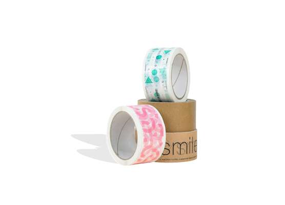Vier Rollen Verpackungsband: zwei braune (eine mit schwarzer Aufschrift) und zwei weiße – eine mit grünen Mustern, die andere mit rosa Mustern