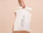 Hand holding a white bio poly mailer with a black text print and die-cut handle