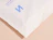Close-up of a white bio poly mailer with a blue logo print and sealed edge
