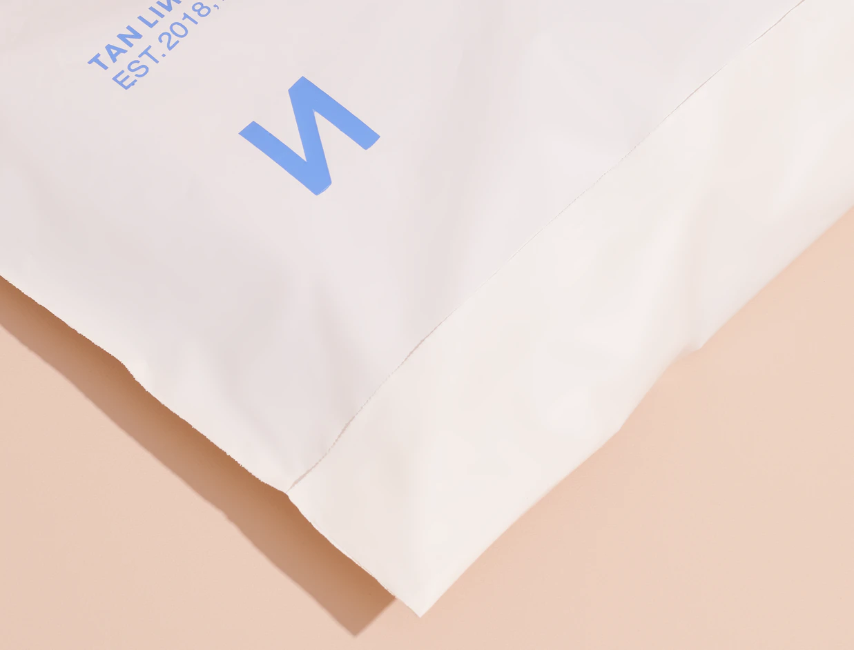 Close-up of a white bio poly mailer with a blue logo print and sealed edge
