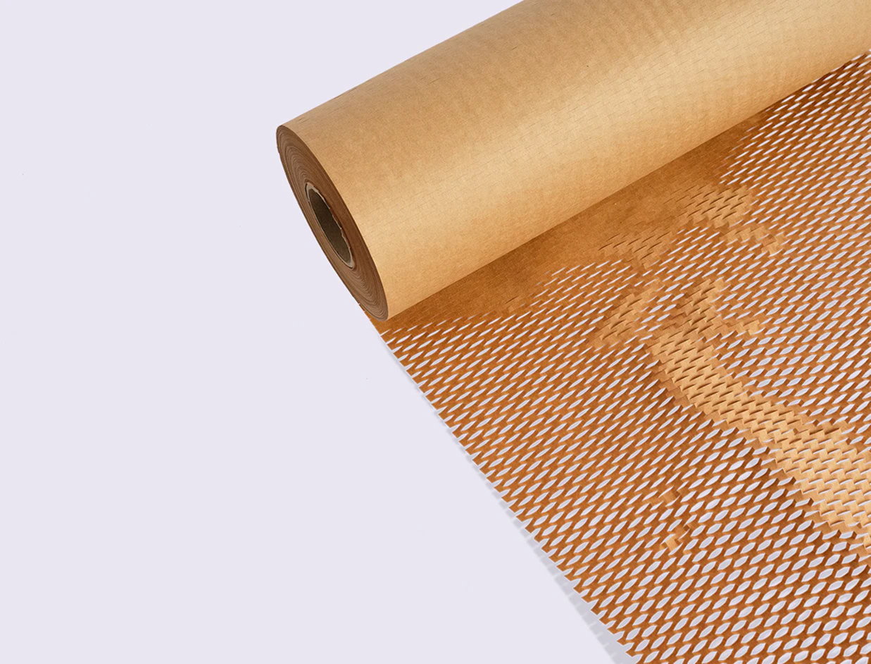 A roll of brown kraft paper with cut-out honeycomb protective mesh unrolling against a white background