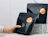 A hand holding a matte black ziplock coffee pouch with an orange round label, displayed in front of another black pouch and a patterned box