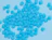 Top-down view of bright blue biodegradable foam packing peanuts scattered across a light blue background