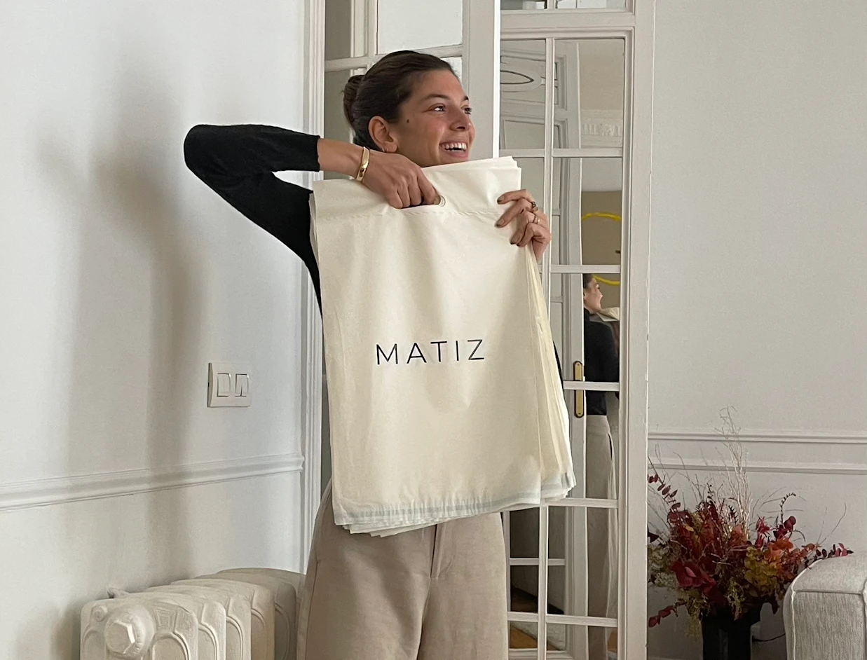Person holding an off-white bio poly mailer with a subtle logo print