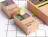 Kraft paper product boxes by Packhelp decorated with green tape on a black and white grid surface
