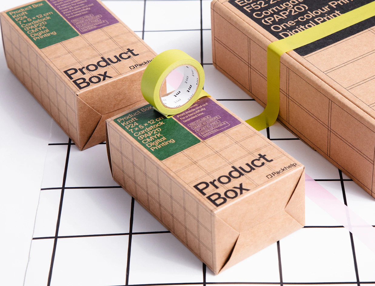 Kraft paper product boxes by Packhelp decorated with green tape on a black and white grid surface
