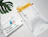 Flat lay of white bio poly mailers printed with eco properties and 'Hi there! I'm fully biodegradable.', one holding a yellow blanket next to a monstera leaf