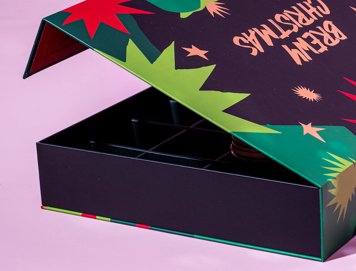 Partially open dark gift box with festive green and red graphics reading 'BREW CHRISTMAS'