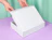Hands opening a plain white cardboard mailer box on a purple surface against a mint green background