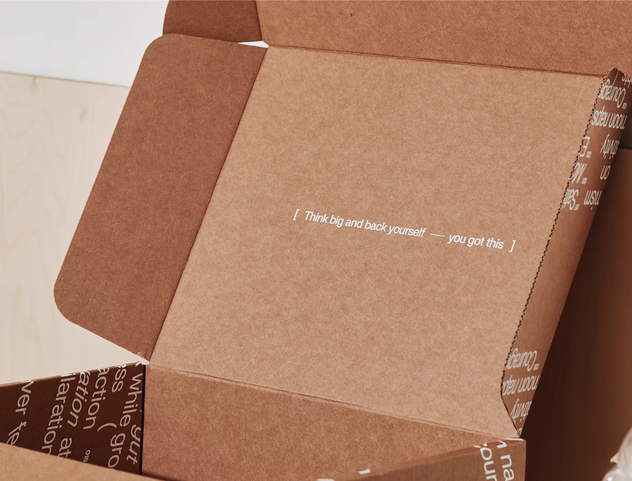 Open kraft mailer box with a white print inside the lid and along the side walls