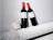 Two wine bottles with rectangular white custom labels next to a label roll
