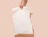 A hand holding a plain white padded poly mailer bag with a die-cut handle against a beige background