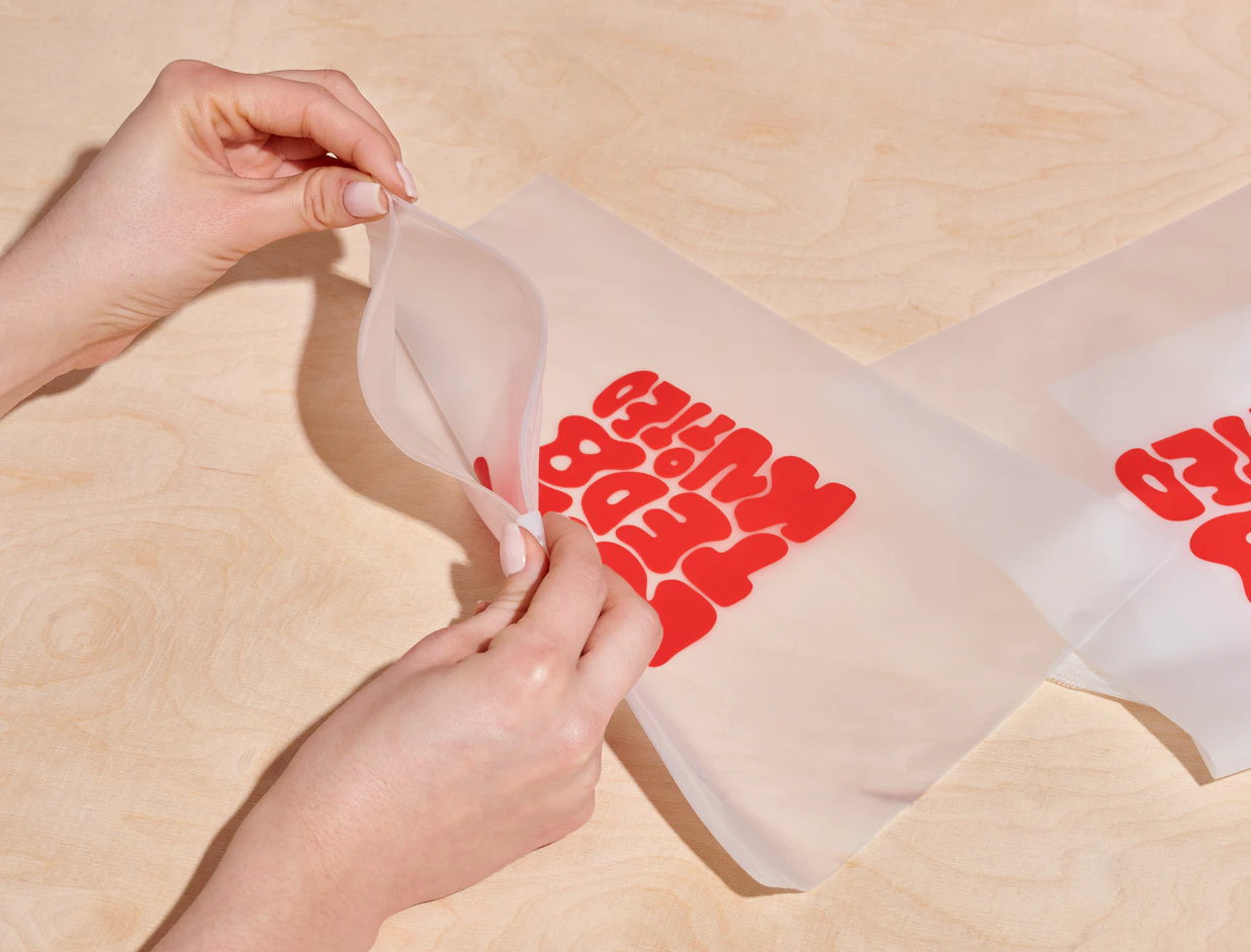 Hands opening a frosted zipper bag with a red lettering print