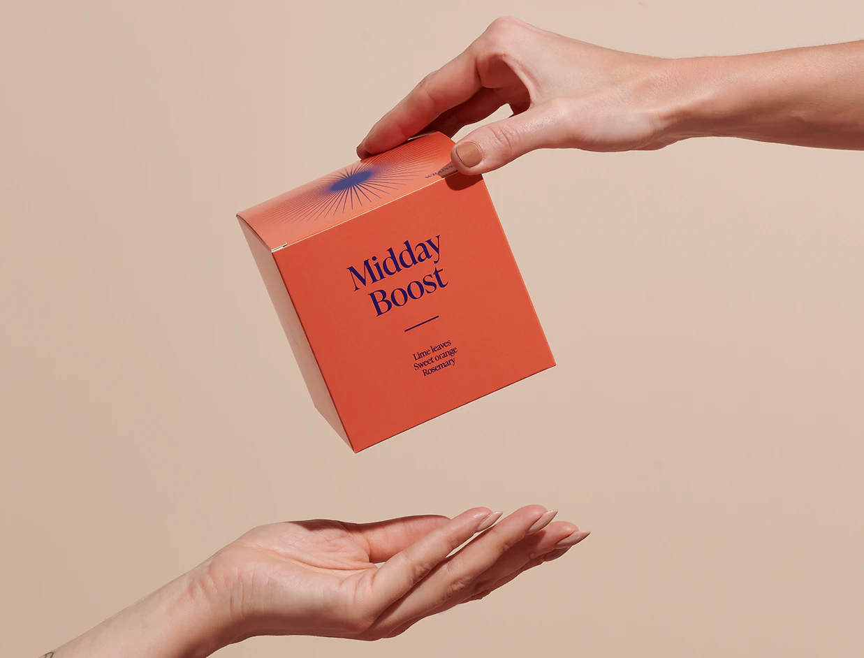 One hand passing an orange square product box labeled 'Midday Boost' to another hand from above