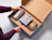 Hands placing blue patterned tin and gift box into a custom cardboard insert inside a shipping box